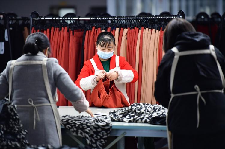 3月11日,在城固县博望街道办事处江湾社区一服装厂内,工人在检查服装